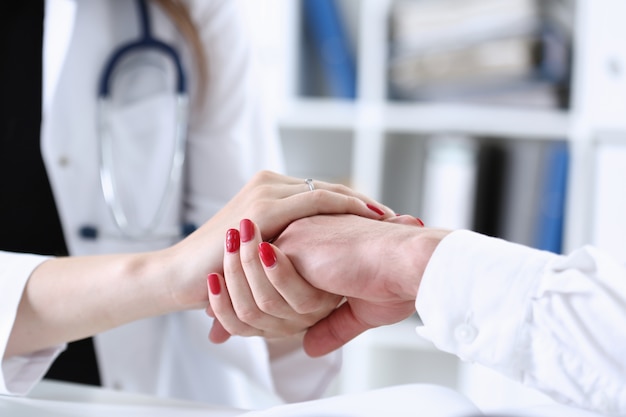 Friendly female doctor hold male patient hand