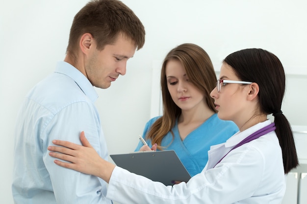 Friendly female doctor touching male patient's arm for encouragement, empathy and support