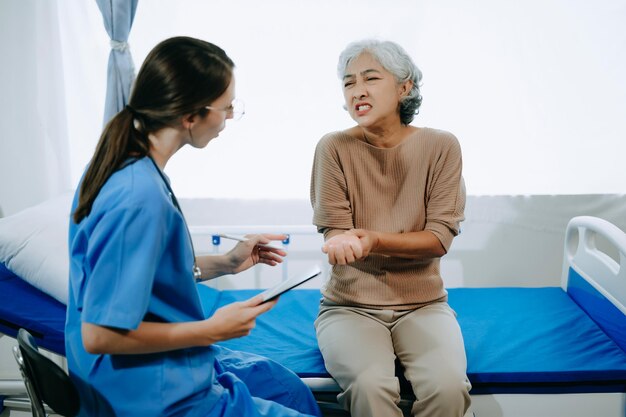 Friendly female head nurse making rounds does checkup on patient resting in bed she checks tablet while man fully recovering after successful surgery in hospital or clinic