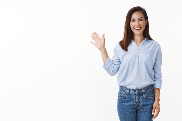 Friendly goodlooking european woman entrepreneur with tattoo joyfully welcome you wave palm gladly invite greet person smiling broadly enthusiastic grin say hi hello stand white background