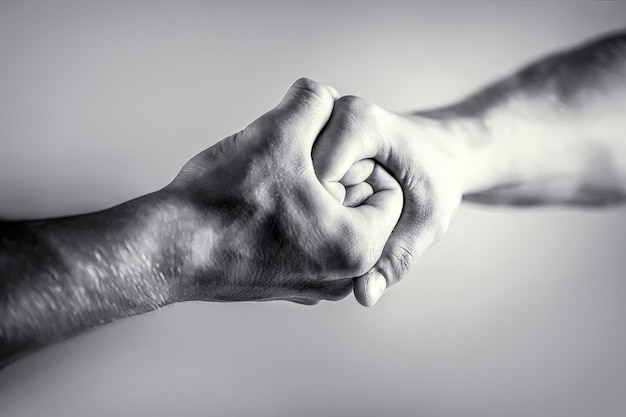 Friendly handshake, friends greeting. Rescue, helping hand. Male hand united in handshake. Man help hands, guardianship, protection. Black and white.