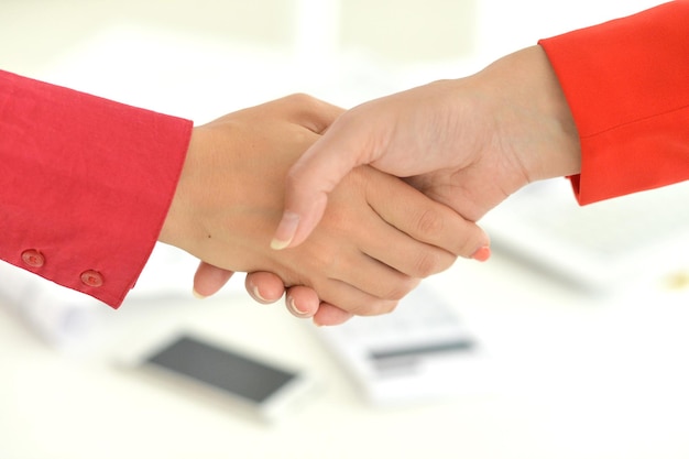 Friendly handshake in the office closing the deal closeup