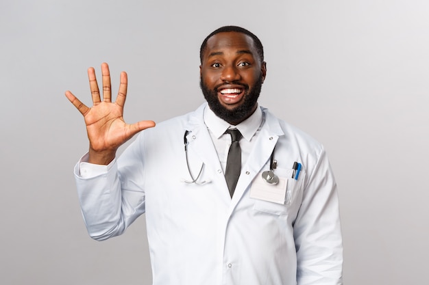 친절 찾고 쾌활한 잘 생긴 흑인 의사, 5를 보여주는 남성 의사