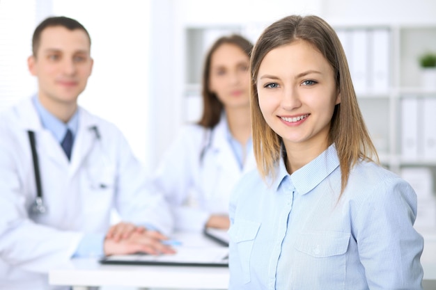 Friendly male doctor  on the background with patient  in hospital. High level and quality medical service concept.