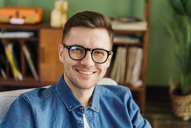 Friendly man in blue denim shirt sitting at home with a warm smile