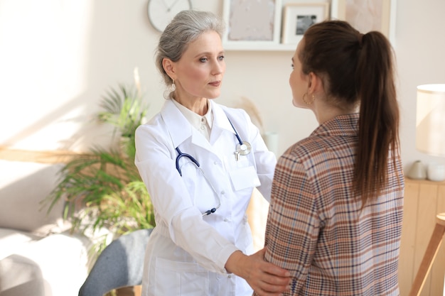 Friendly middle aged female doctor encouraging, supporting patient after medical examination.