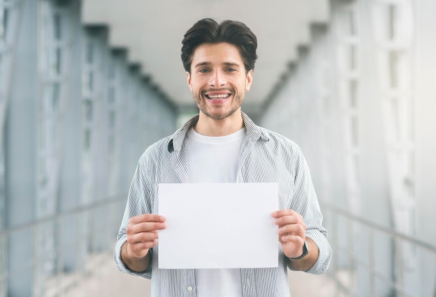 Friendly millennial man holding name board at airport