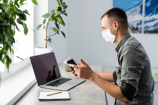 Foto amichevole impiegato d'ufficio che indossa una maschera igienica e saluta a gesti, utilizzando il filtro di protezione contro la malattia contagiosa coronavirus, 2019-ncov, epidemia di influenza. girato in studio isolato su sfondo bianco.