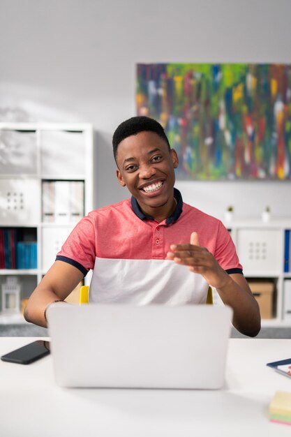 A friendly office worker welcomes the customer sits behind a desk in front of a laptop