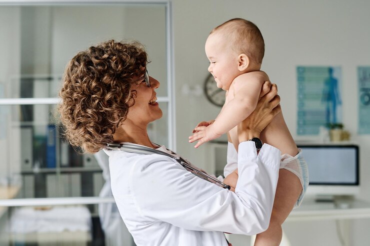 Photo friendly pediatrician holding baby on arms and smiling she examining her during medical exam