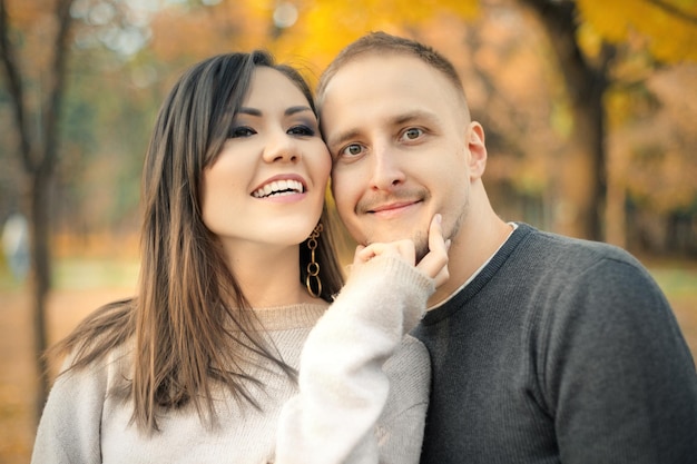 Friendly portrait of asian young beautiful young woman and young caucasian man in autumn outdoor