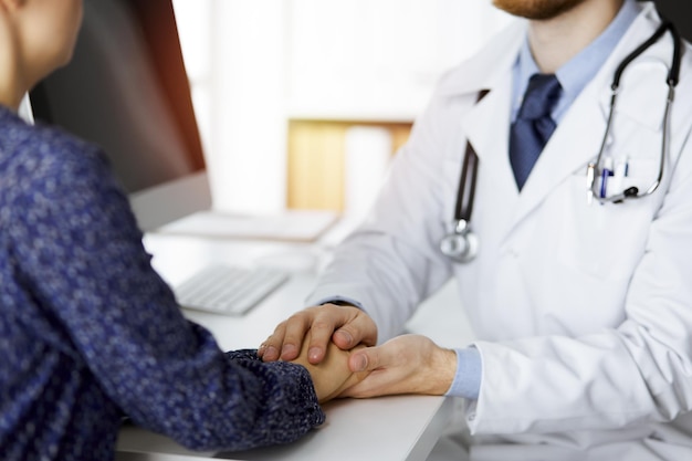 Friendly red-beard doctor reassuring his female patient, close-up. Medical ethics and trust concept, medicine theme.