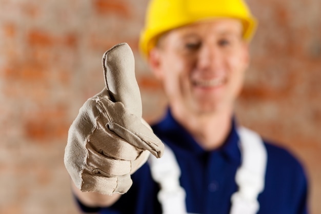 Friendly and reliable construction worker giving thumbs up, focus on thumb