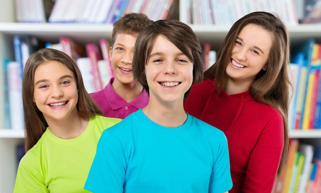 Friendly school children in library on background