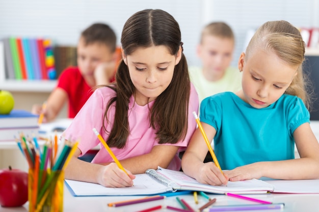 Friendly school children with books at class