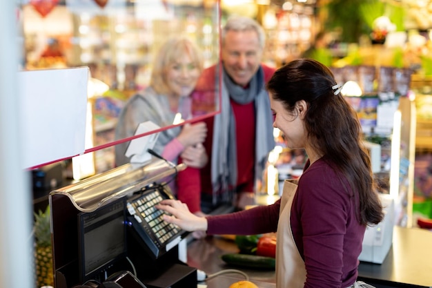 friendly senior husband and wife having conversation with cashier