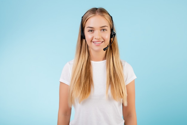 Friendly smiling blonde call center operator with headset isolated over blue