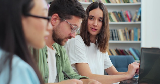 Friendly students sit at desk in library writing discuss\
collaborative project preparing for high school exams university\
education study concept