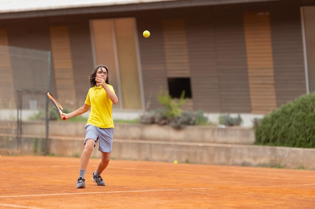 少年がボールをサーブする親善テニスの試合