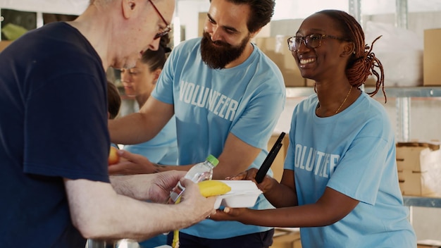 Friendly volunteers distribute generous food donations to homeless people showing impact of charitable works. Close-up of voluntary individuals serving and sharing warm meals to the less fortunate.