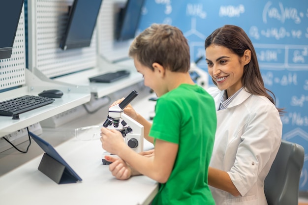 Friendly woman showing microscope to boy