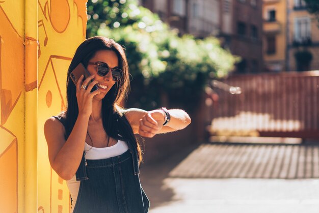 Amichevole donna parla al cellulare e guarda l'ora