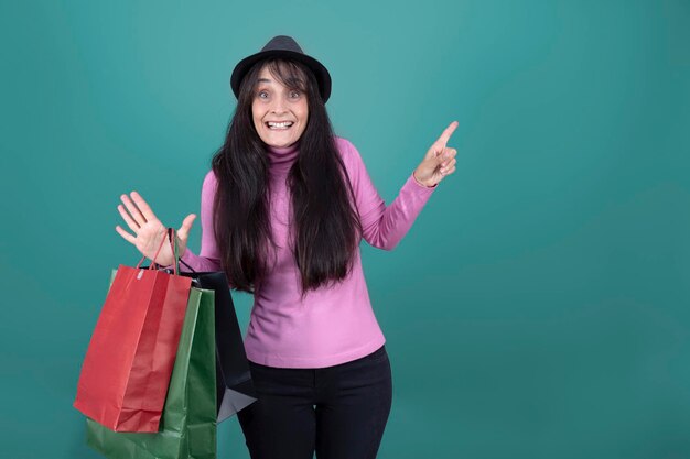 The friendly woman with paper shopping bags pink sweater and black hat isolated from the background