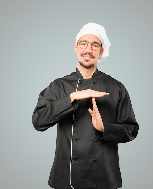 Friendly young chef making a time out gesture with his hands