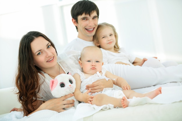 Friendly young family lying on bed together .the concept of parenthood.