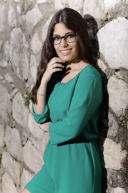 Friendly young lady leaning on stone wall