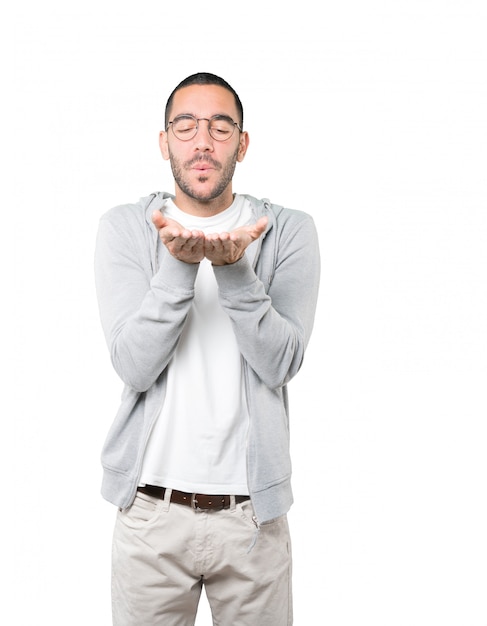 Friendly young man making a gesture of sending a kiss with his hand