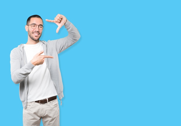 Friendly young man making a gesture of taking a photo with the hands