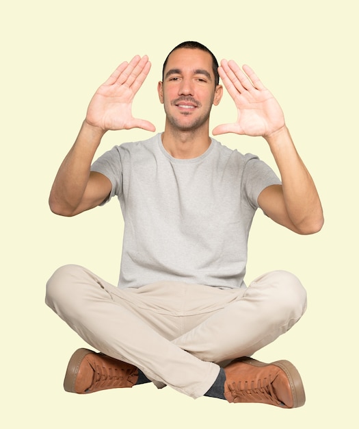 Friendly young man making a gesture of taking a photo with the hands