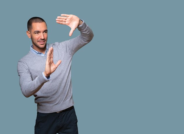 Friendly young man making a gesture of taking a photo with the hands