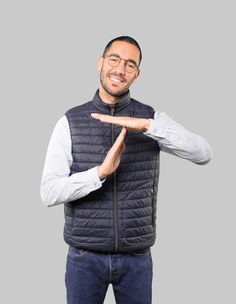 Friendly young man making a time out gesture with his hands