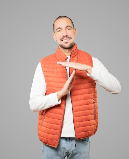 Friendly young man making a time out gesture with his hands