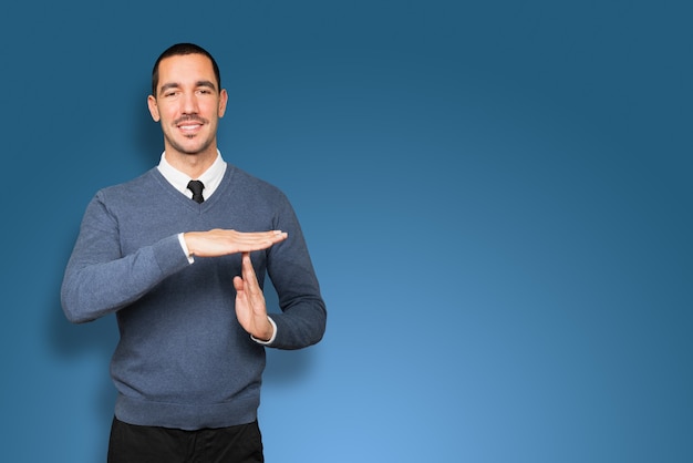 Friendly young man making a time out gesture with his hands