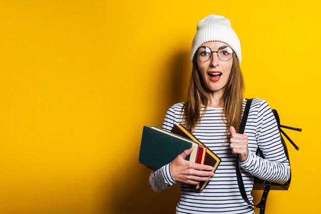 黄色の背景に本を読んでフレンドリーな若い女性