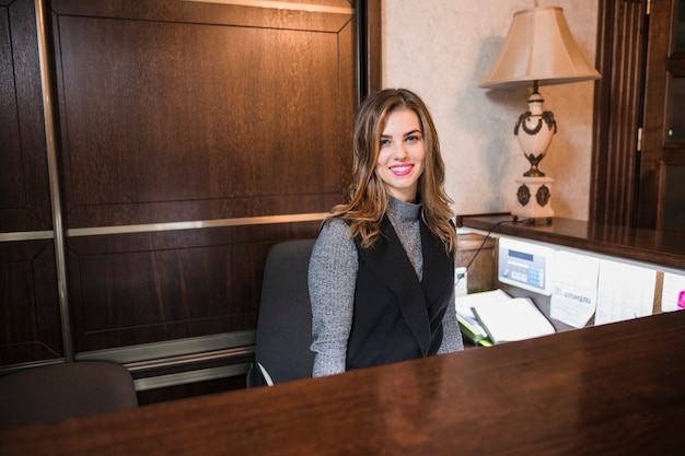Photo friendly young woman behind the reception desk administrator