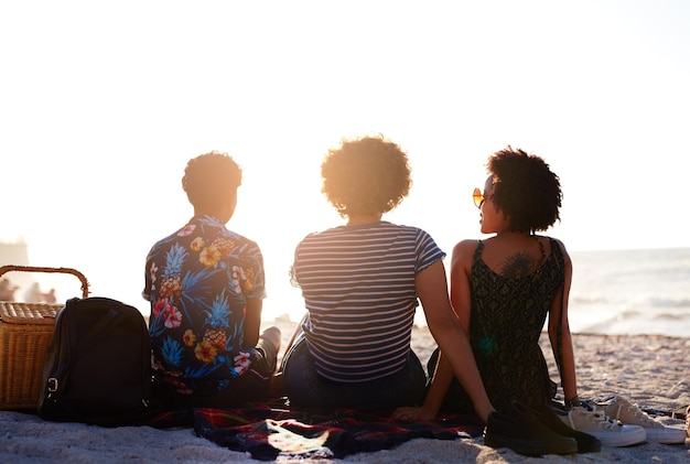 Друзья — это те, ради кого стоит жить. Вид сзади неузнаваемой трио женщин, устраивающих пикник на пляже в течение дня.