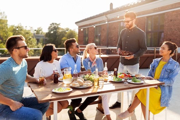 friends at barbecue party on rooftop in summer