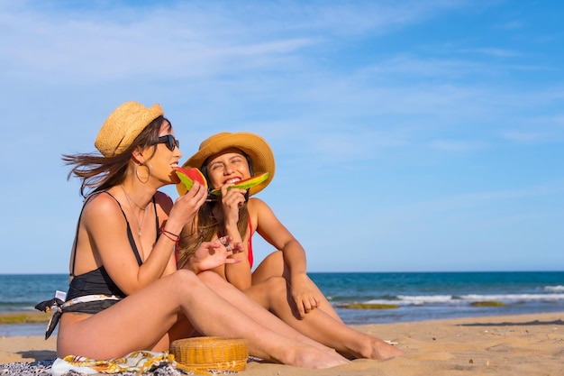 Friends on the beach in summer eating a watermelon with the sea in the background vacation concept