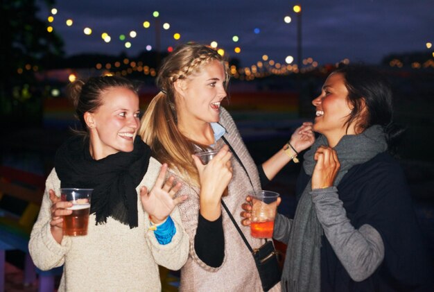 Foto amici birra all'aperto di notte o festival musicale in foresta avventura celebrazione della natura o connessione di gruppo faccia di donna e sorriso per bere alcol o acclamazioni brindisi per viaggi estivi o vacanze