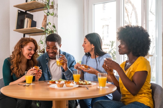 Friends at a breakfast with orange juice and muffins at home having fun in the morning