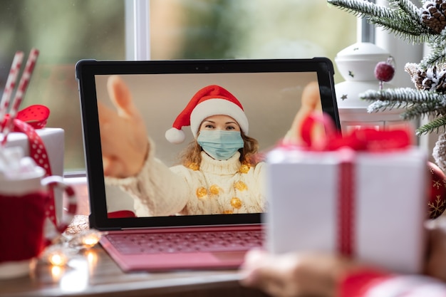 Friends celebrating Christmas holiday online by video chat in quarantine. Lockdown stay home concept. Xmas family party during pandemic coronavirus COVID 19