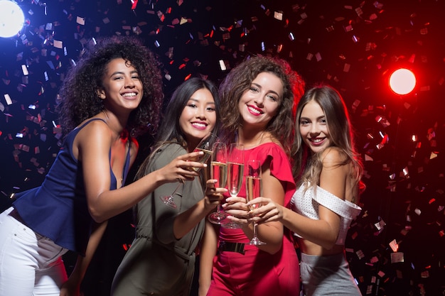 Friends celebrating Christmas or New Year eve with champagne, toasting at camera