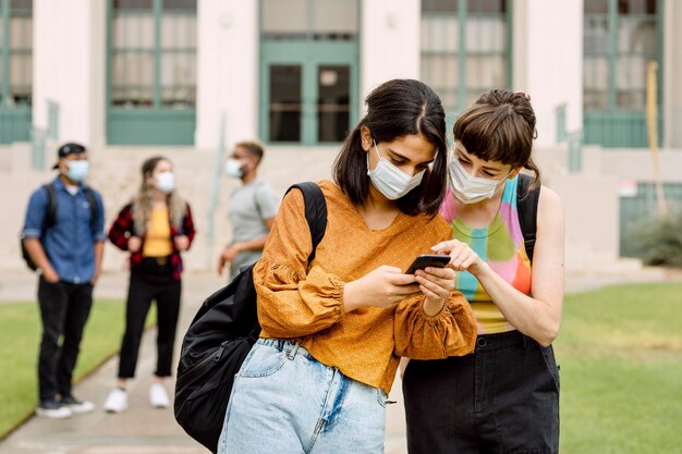 friends checking social media on phone at school