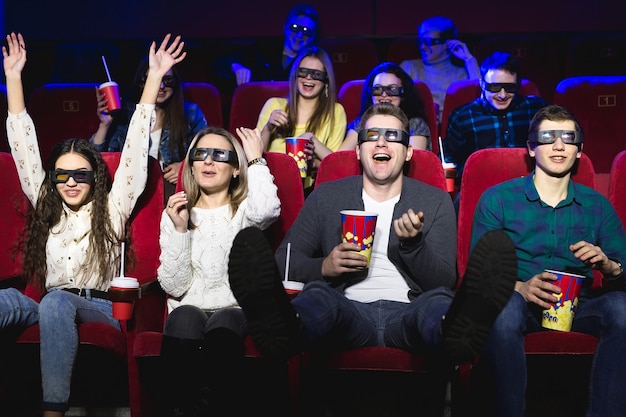 Friends at the cinema watch a funny movie with 3D glasses