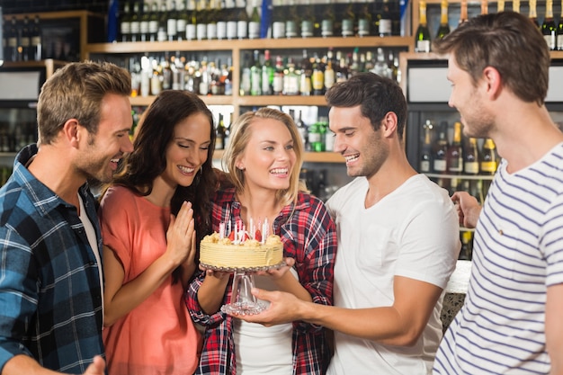 Friends in a circle holding a cake