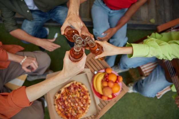 Friends clinking beer bottles view from top